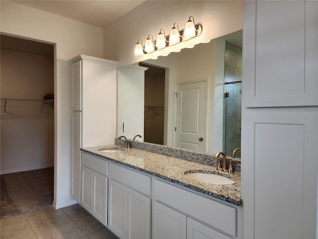 bathroom featuring tile patterned floors, tiled shower, double vanity, and a sink