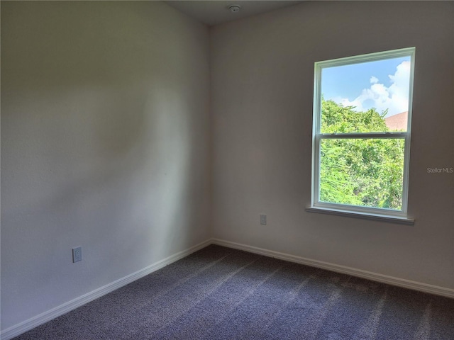 unfurnished room featuring baseboards and dark colored carpet