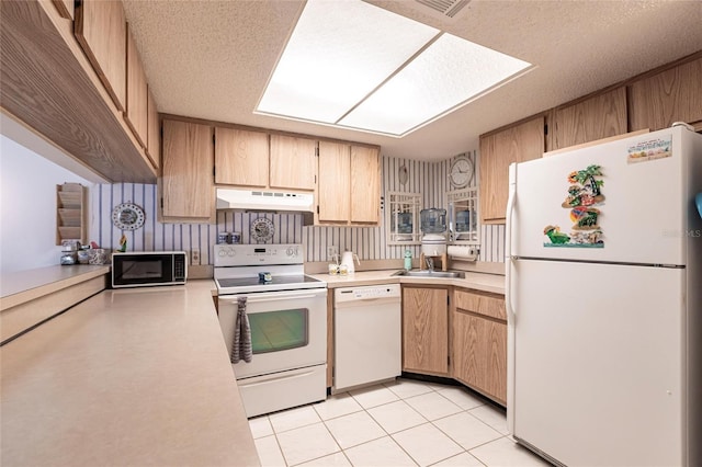 kitchen with under cabinet range hood, white appliances, a sink, and light countertops