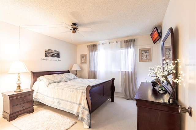 bedroom with ceiling fan, light colored carpet, and a textured ceiling