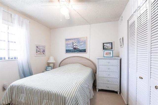 bedroom with a closet, a textured ceiling, ceiling fan, and carpet floors