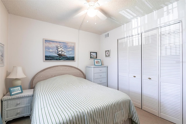 bedroom featuring visible vents, ceiling fan, carpet flooring, a closet, and a textured ceiling