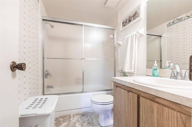 bathroom with toilet, vanity, and shower / bath combination with glass door