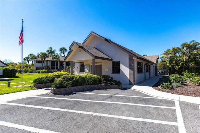 view of front of property featuring stucco siding, uncovered parking, and a front yard