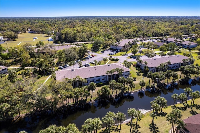 drone / aerial view with a wooded view and a water view