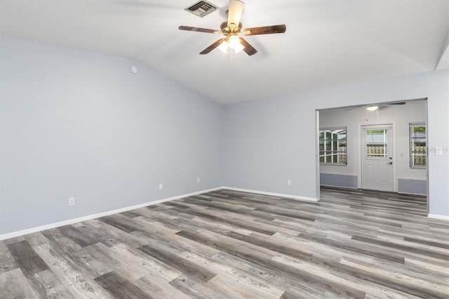 spare room with wood finished floors, baseboards, visible vents, lofted ceiling, and ceiling fan