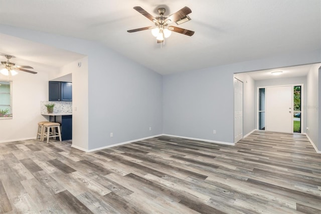 unfurnished living room featuring baseboards, lofted ceiling, ceiling fan, and wood finished floors