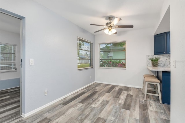 unfurnished living room with wood finished floors, a ceiling fan, and baseboards