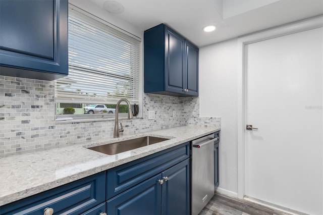 kitchen with wood finished floors, a sink, decorative backsplash, stainless steel dishwasher, and blue cabinets