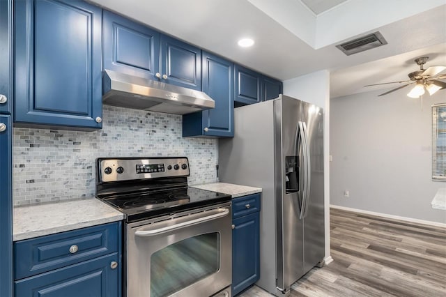 kitchen with visible vents, blue cabinetry, stainless steel appliances, decorative backsplash, and under cabinet range hood