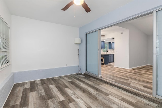 empty room with a ceiling fan, wood finished floors, and baseboards