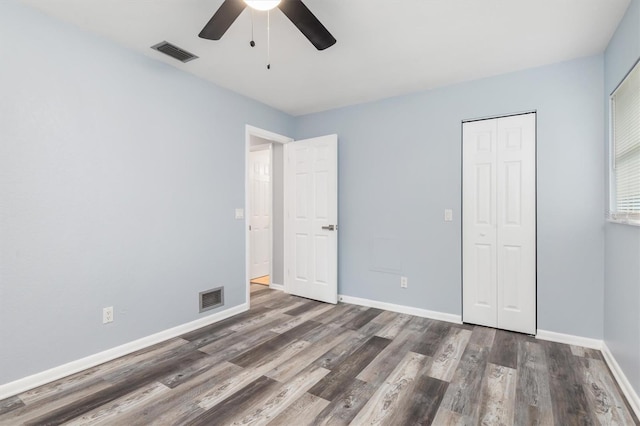 unfurnished bedroom with a closet, visible vents, baseboards, and wood finished floors