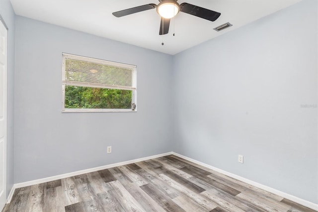 unfurnished room with ceiling fan, wood finished floors, visible vents, and baseboards