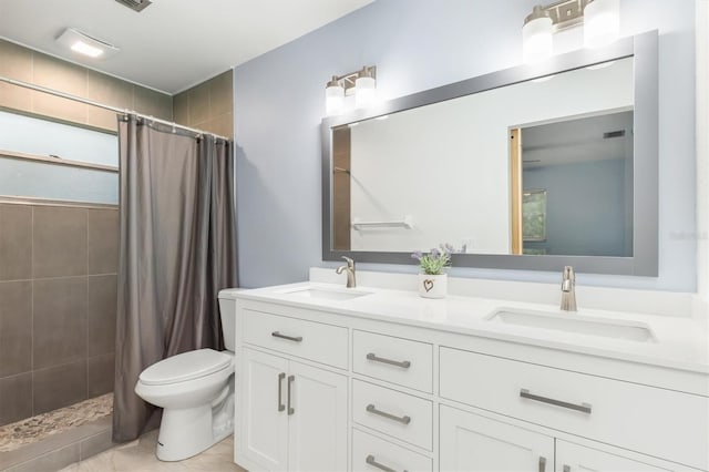 bathroom with double vanity, toilet, a tile shower, and a sink