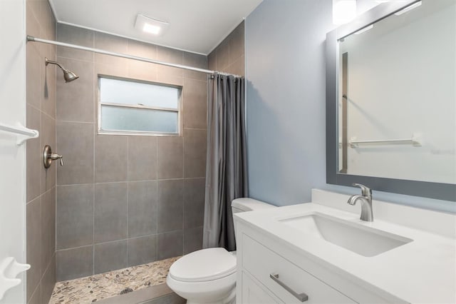 full bathroom featuring vanity, toilet, and a tile shower