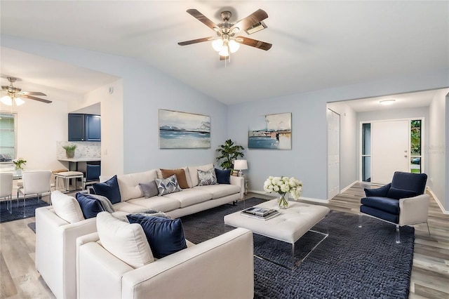 living area featuring vaulted ceiling, a ceiling fan, baseboards, and light wood finished floors