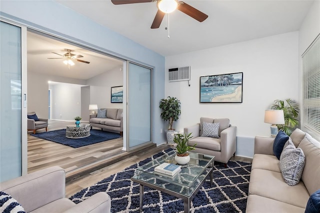 living area with wood finished floors, ceiling fan, and a wall unit AC