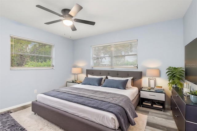 bedroom with multiple windows, baseboards, ceiling fan, and wood finished floors