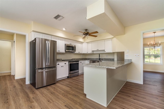 kitchen featuring appliances with stainless steel finishes, a peninsula, dark wood-style flooring, and white cabinetry