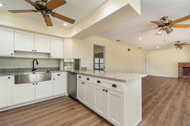 kitchen featuring light wood-style flooring, dishwasher, a peninsula, and a sink