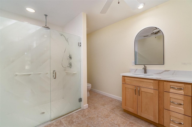 bathroom with vanity, a ceiling fan, baseboards, a shower stall, and toilet