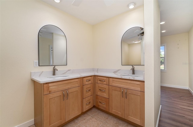 full bath featuring double vanity, a ceiling fan, and a sink