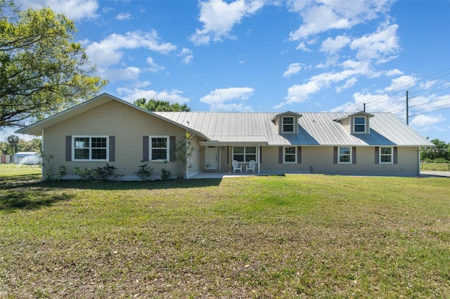 view of front of property featuring a front lawn, metal roof, and a patio