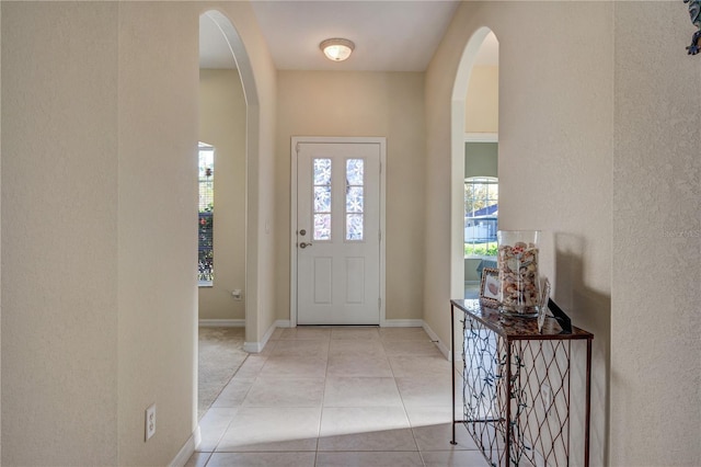 tiled foyer with baseboards and arched walkways