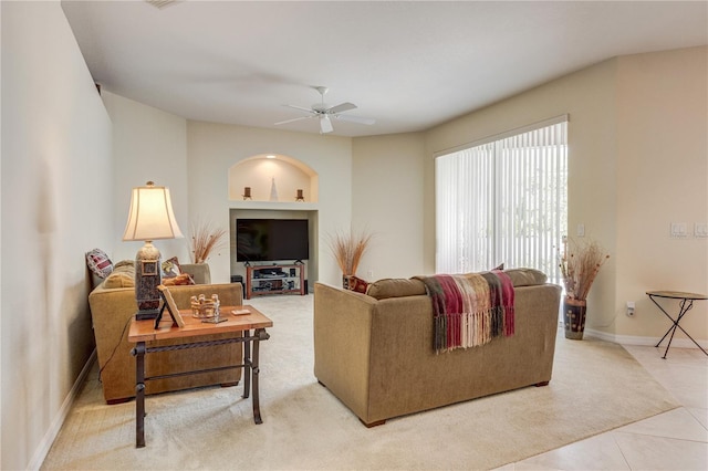 living area with light tile patterned flooring, baseboards, and ceiling fan