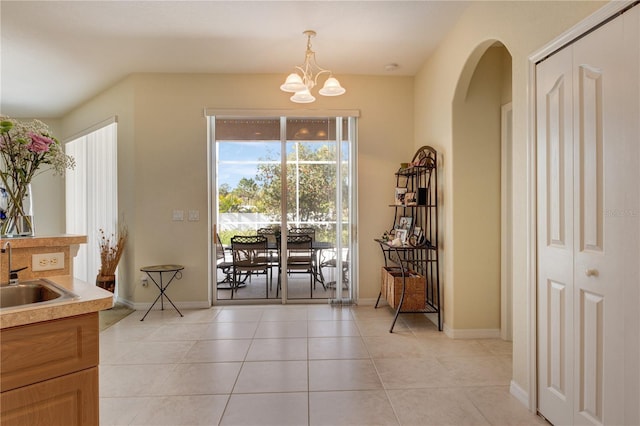 dining room featuring light tile patterned flooring, a notable chandelier, arched walkways, and baseboards