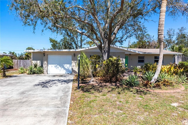 ranch-style home with fence, a garage, driveway, and stucco siding