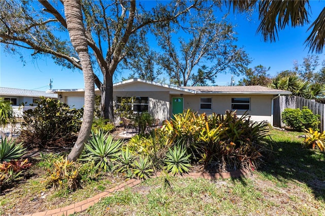 ranch-style house featuring fence, a garage, and stucco siding