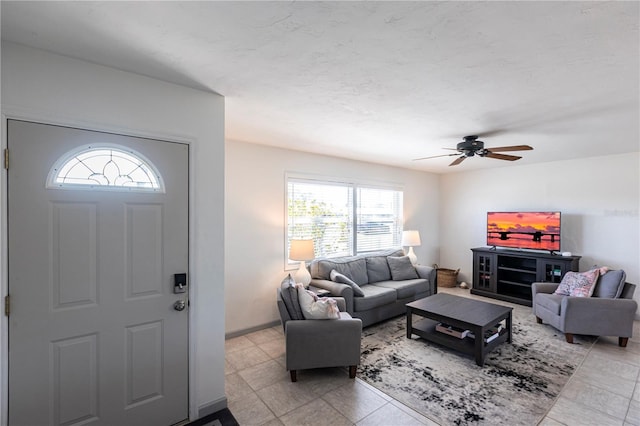 living area with baseboards and ceiling fan