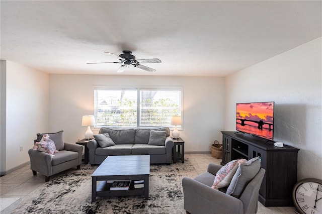 living area with baseboards and ceiling fan