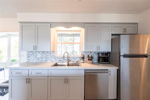 kitchen with gray cabinets, stainless steel appliances, light countertops, and a sink