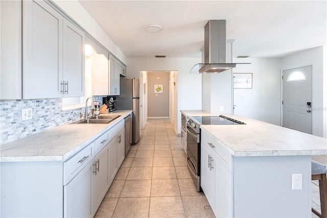 kitchen with island exhaust hood, light countertops, stainless steel appliances, and a sink