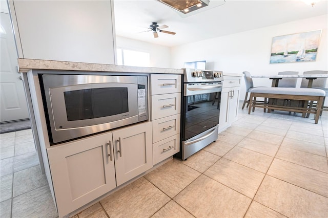 kitchen with light tile patterned floors, stainless steel appliances, a ceiling fan, and light countertops