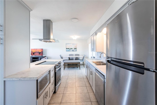 kitchen with light countertops, light tile patterned floors, appliances with stainless steel finishes, island exhaust hood, and a sink