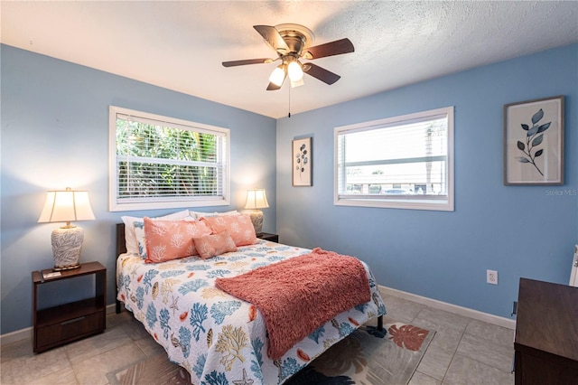 bedroom featuring tile patterned floors, ceiling fan, a textured ceiling, and baseboards