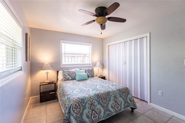 bedroom featuring multiple windows, a textured ceiling, and baseboards