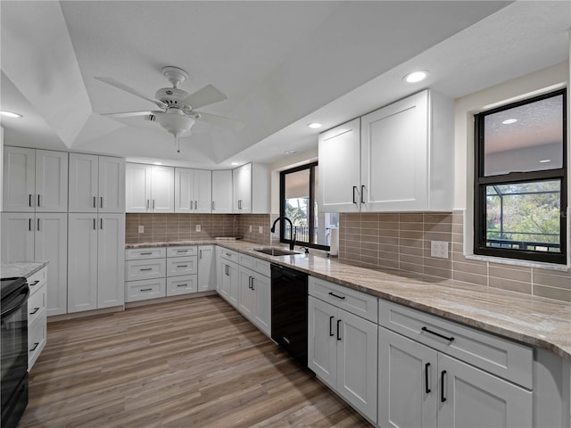 kitchen featuring tasteful backsplash, black appliances, light wood-style floors, white cabinetry, and a sink