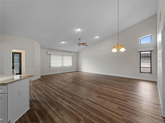 unfurnished living room with ceiling fan with notable chandelier, plenty of natural light, baseboards, and dark wood-style flooring