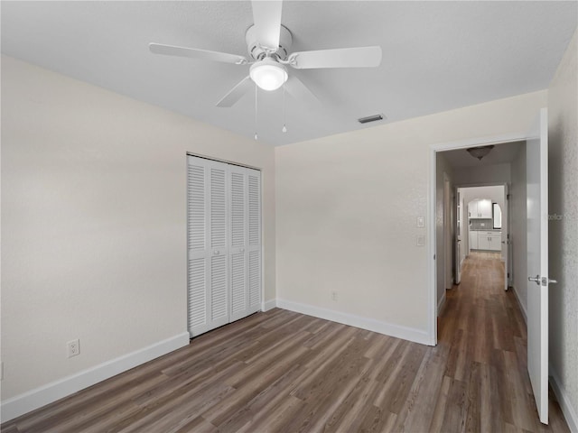 unfurnished bedroom with a closet, visible vents, baseboards, and wood finished floors