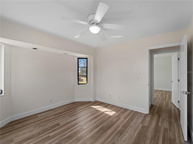 empty room with wood finished floors, baseboards, and ceiling fan