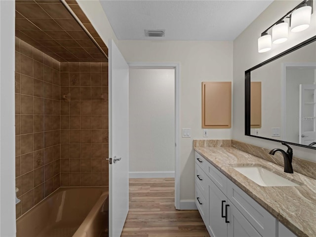 full bath featuring visible vents, wood finished floors, baseboards, bathing tub / shower combination, and vanity