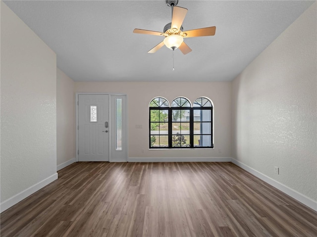 foyer featuring wood finished floors, baseboards, and a textured wall