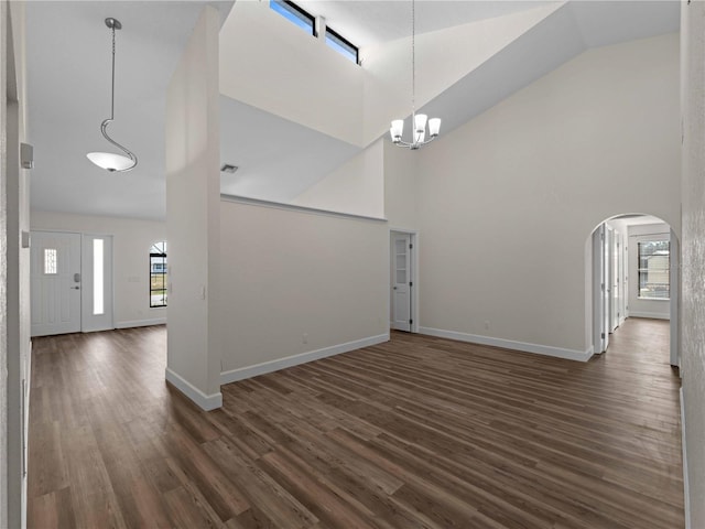 entryway featuring high vaulted ceiling, dark wood finished floors, arched walkways, an inviting chandelier, and baseboards