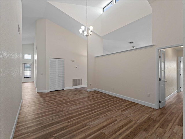 interior space featuring wood finished floors, visible vents, baseboards, an inviting chandelier, and a high ceiling