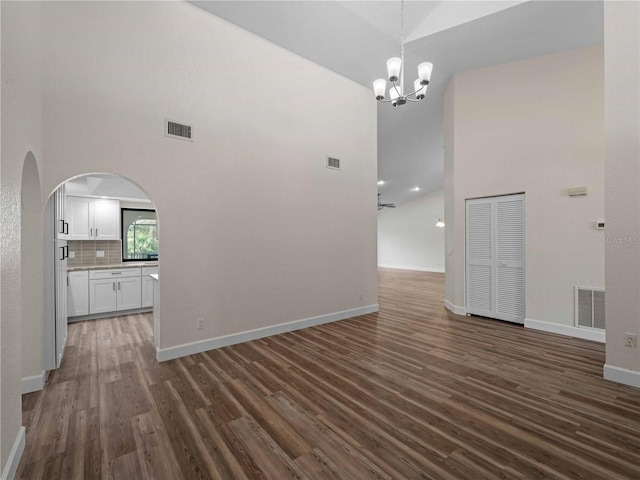 interior space featuring arched walkways, visible vents, high vaulted ceiling, and dark wood-style flooring