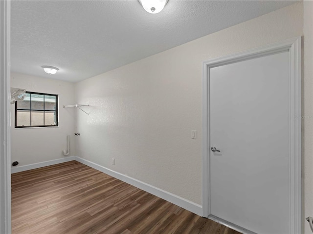 spare room with a textured ceiling, baseboards, and wood finished floors